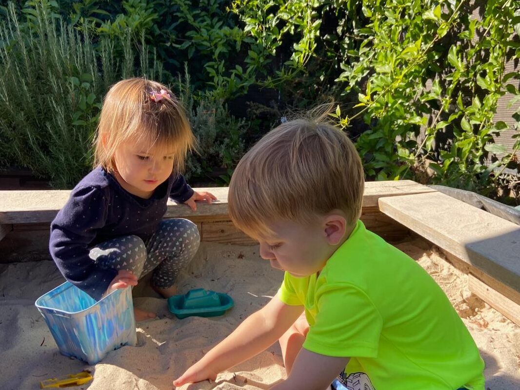 Two toddlers playing in the sandbox