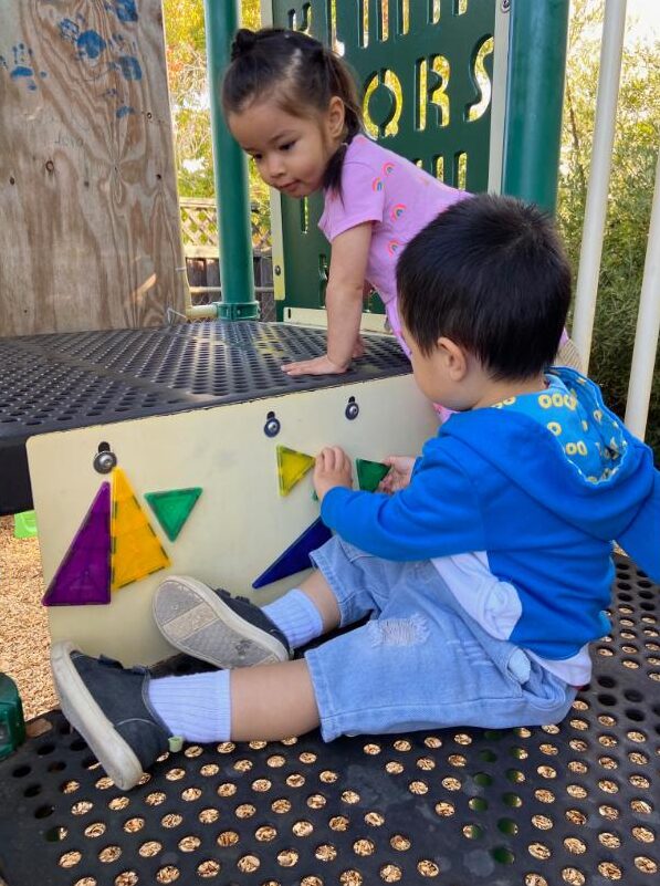 Children fitting shapes on the playground learning panel
