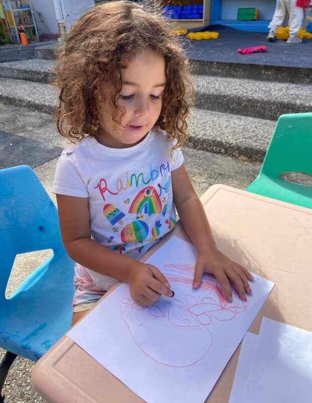 A preschooler drawing at an outdoor table