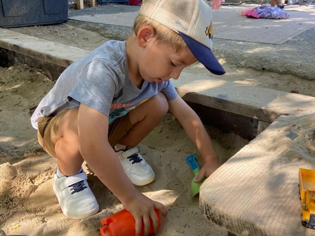 A toddler digging in the sandbox