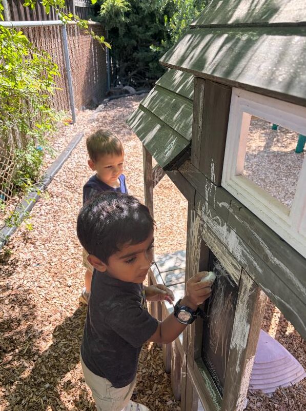 Children drawing with chalk on the playhouse chalkboard