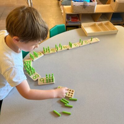 A child lining up dominoes at the table