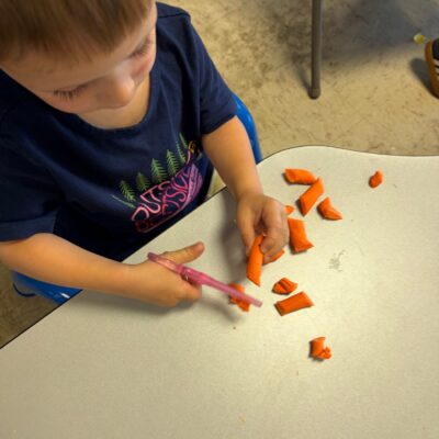 A child cutting modeling dough at the table