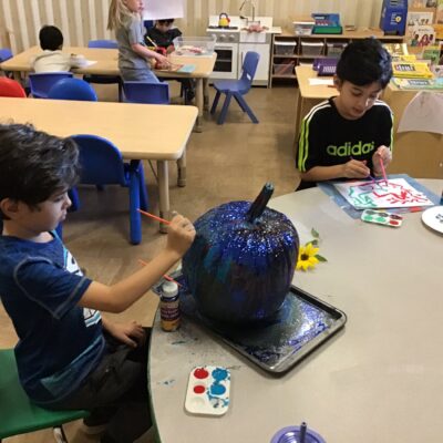 Children painting a large pumpkin together