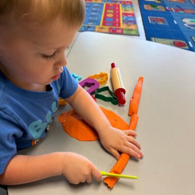A child shaping modeling dough at the table
