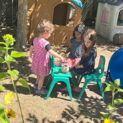 A teacher and children gathered at a table in the garden