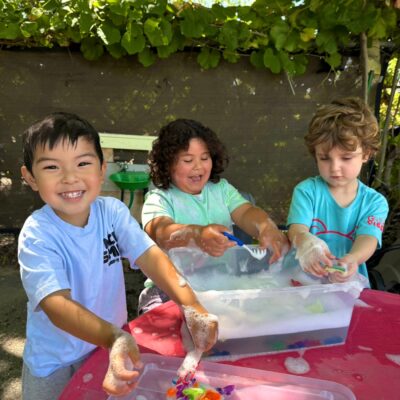 Children exploring a sensory tray at the outdoor table