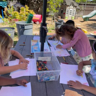 Children drawing with crayons at the outdoor table
